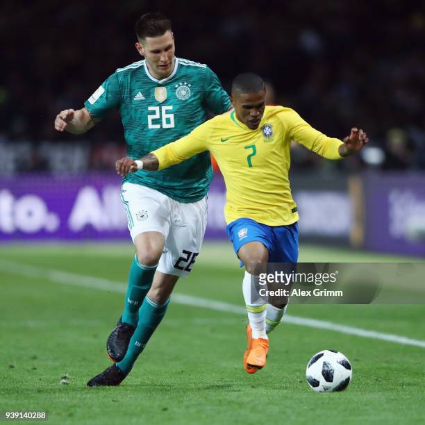 Niklas Suele of Germany is challenged by Douglas Costa of Brazil during the international friendly match between Germany and Brazil at Olympiastadion...