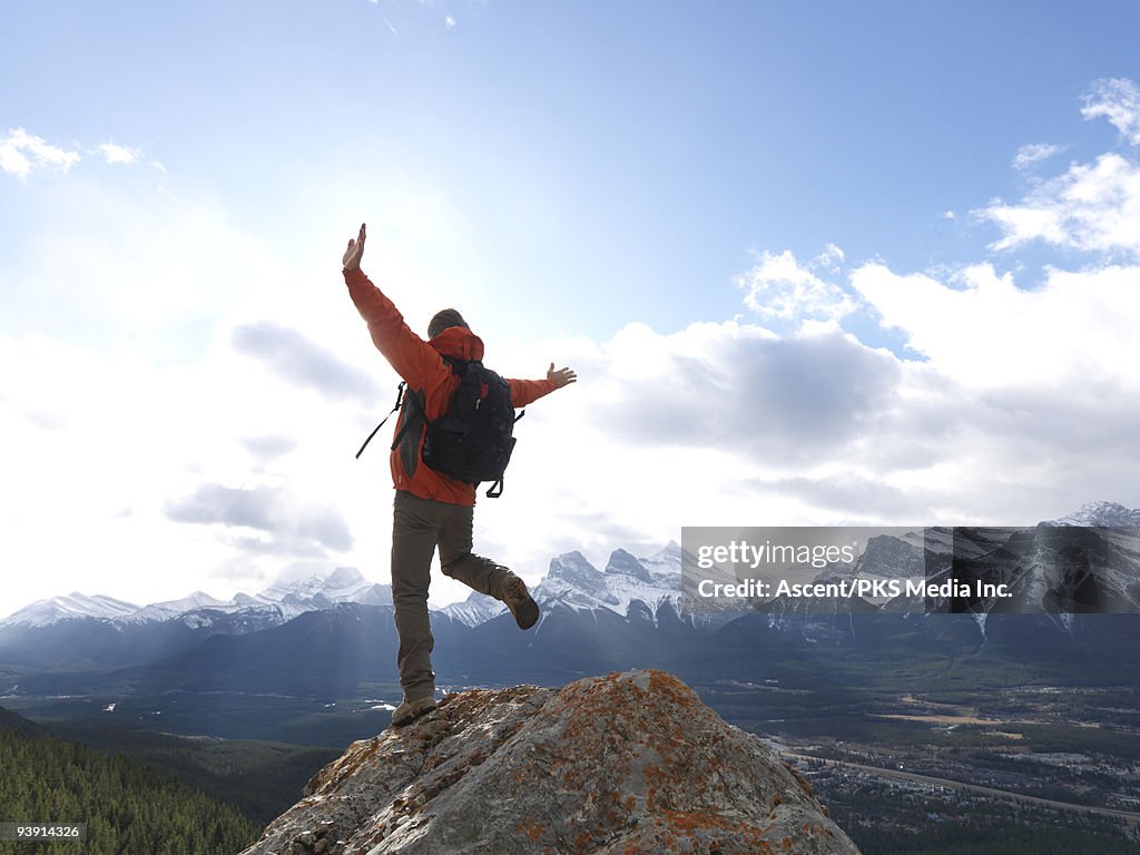 Mountaineer balances on ridge crest, above valley