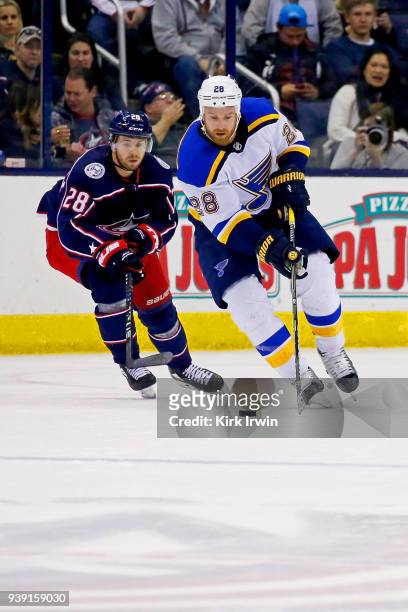 Kyle Brodziak of the St. Louis Blues skates the puck away from Oliver Bjorkstrand of the Columbus Blue Jackets during the game on March 24, 2018 at...