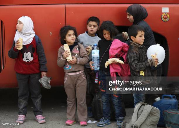 Syrians children eat sandwiches as civilians and rebels evacuated from the Eastern Ghouta region arrive in Qalaat al-Madiq, some 45 kilometres...