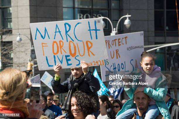 View of demonstrators, two of whom are children on the shoulders of adults, as they participate in the March For Our Lives rally against gun...