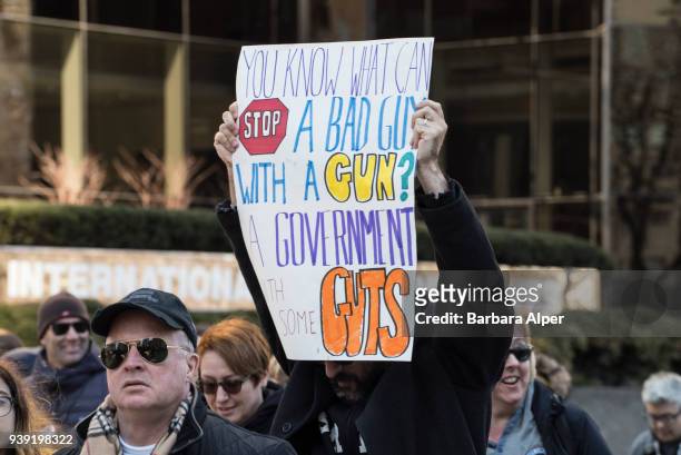 View of demonstrator as he holds up a sign that reads 'You Know What Stops a Bad Guy With a Gun? A Government With Some Guts,' during the March For...