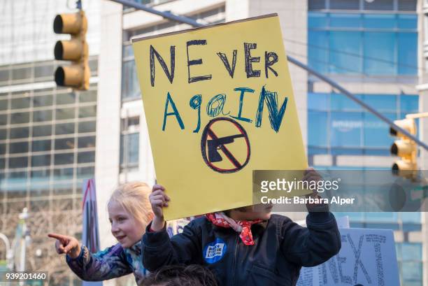 View of a young demonstrator, on someone's shoulders, as she holds a sign that reads 'Never Again' during the March For Our Lives rally against gun...