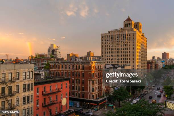 rainbow appears behind the rows of buildings during the dusk at east village manhattan new york, ny, usa - july 01 2017. - east village stock-fotos und bilder