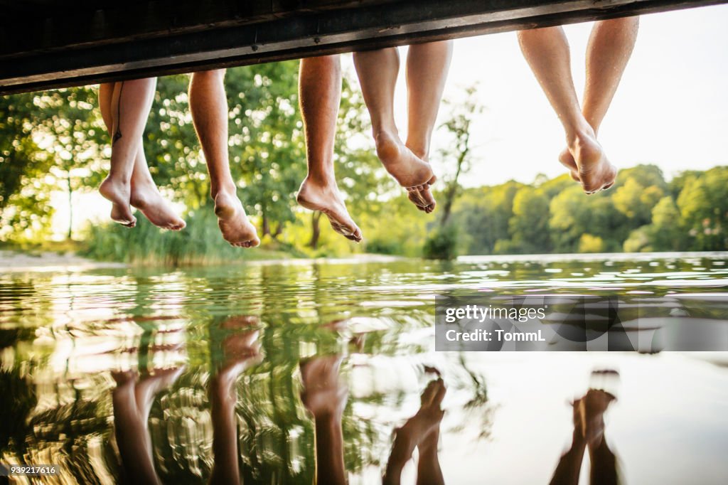 Groep van vrienden poten bungelend uit Jetty