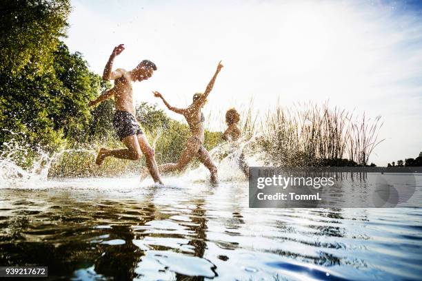 vrienden samen spetteren in water bij lake - mens lifestyle stockfoto's en -beelden