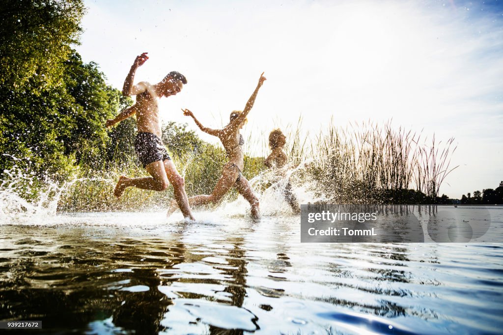 Friends Splashing In Water At Lake Together