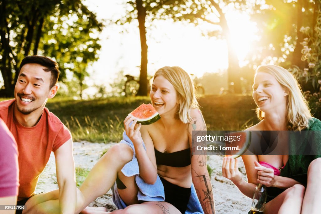 Zwei junge Frauen Essen Wassermelone mit Freunden am Grill