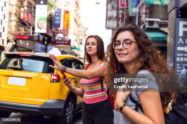 friends traveling abroad to asia waiting for a taxi on the street - ximen stock pictures, royalty-free photos & images