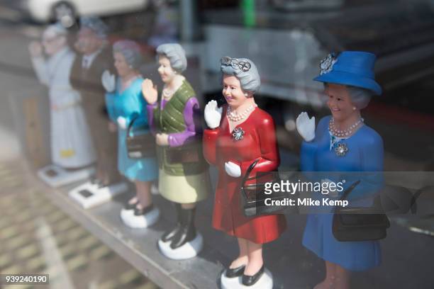 Queen Elizabeth II waving figurines wearing different outfits for sale at a souvenir shop in London, England, United Kingdom.