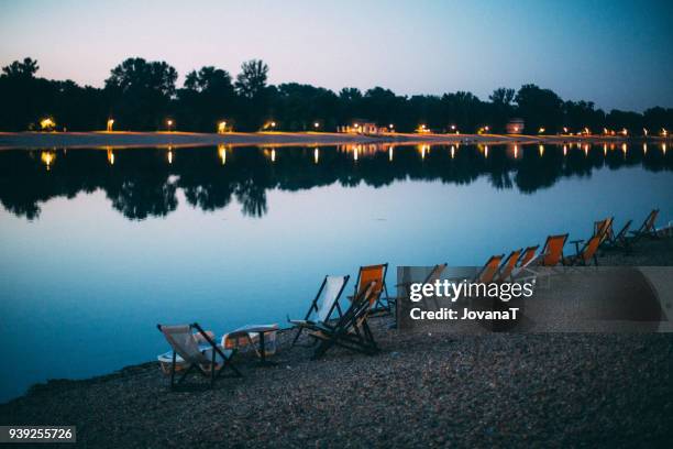 orange sunbeds in evening on lake - jovanat stock pictures, royalty-free photos & images