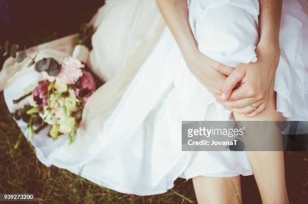 bride sitting on grass with her wedding bouquet - jovanat stock pictures, royalty-free photos & images