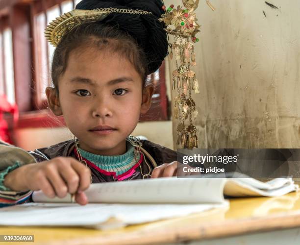 concentrated learner school, writing. looking away, selective focus, small dong village, huang gang."nchild is dressed in traditional dong clothing.the dong is a minority people in china. - gang dong stock pictures, royalty-free photos & images