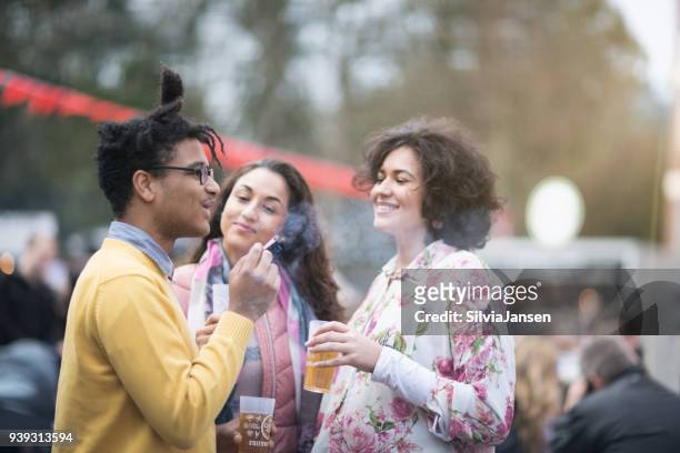 festival: vrienden hebben samen een drankje en een cigaret roken - alcohol and smoking stockfoto's en -beelden