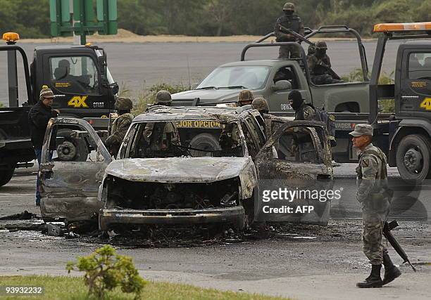 Mexican Army inspect a burned car after a shooting in Juarez, Nuevo Leon state on December 4, 2009. Ten suspected drug traffickers and a woman...
