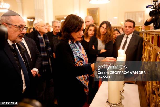 Mayor of Paris Anne Hidalgo lights a candle as Conseil Representatif des Institutuions Juives de France President Francis Kalifat looks on with...