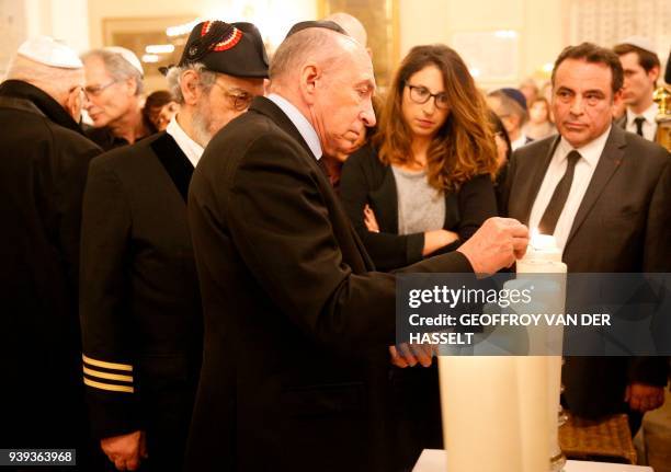 French Interior Minister Gerard Collomb lights a candle in The Synagogue des Tournelles in Paris on March 28 during a service in memory of Mireille...