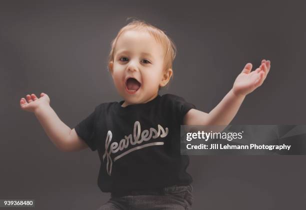 20 month toddler waves arms in excitement with shirt that says "fearless" - angelic model stock pictures, royalty-free photos & images