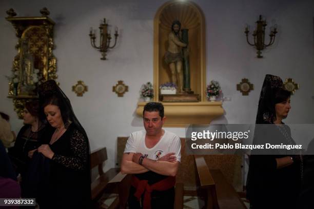 Women wearing mantilla, and a costalero from La Pasion brotherhood wait for the start of a procession at Nuestra Senora de la Paz Church during...