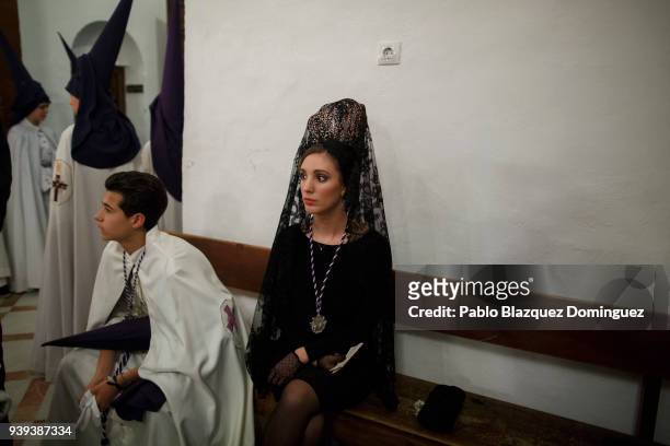 Woman wearing mantilla, and penitents from La Pasion brotherhood wait for the start of a procession at Nuestra Senora de la Paz Church during Easter...