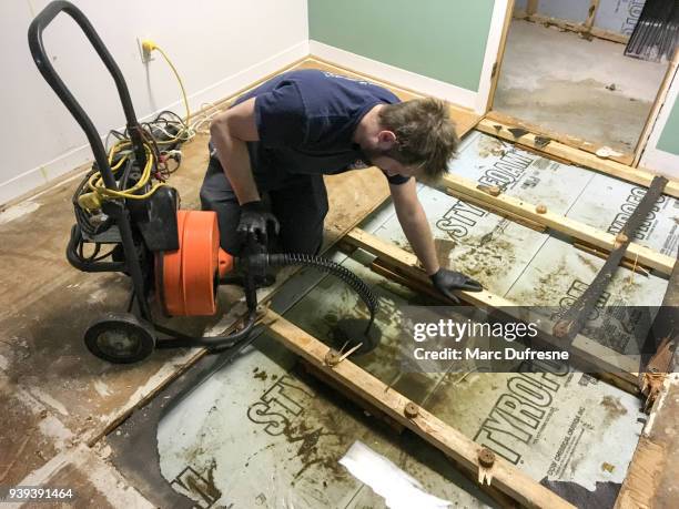 plumber pushing a plunger drain into drain to unclog it - flooded basement imagens e fotografias de stock