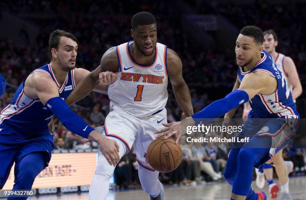 Dario Saric and Ben Simmons of the Philadelphia 76ers reach for the ball against Emmanuel Mudiay of the New York Knicks in the fourth quarter at the...