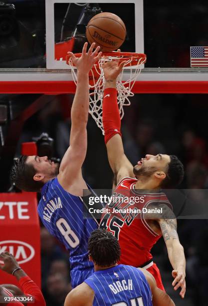 Denzel Valentine of the Chicago Bulls tries to block a shot by Mario Hezonja of the Orlando Magic at the United Center on February 12, 2018 in...