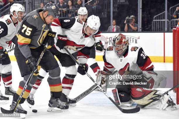 Jakob Chychrun and Antti Raanta of the Arizona Coyotes defend their goal against Ryan Reaves of the Vegas Golden Knights during the game at T-Mobile...