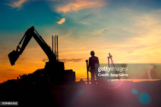 construction equipment's silhouette on sunset - baustelle bagger stock-fotos und bilder