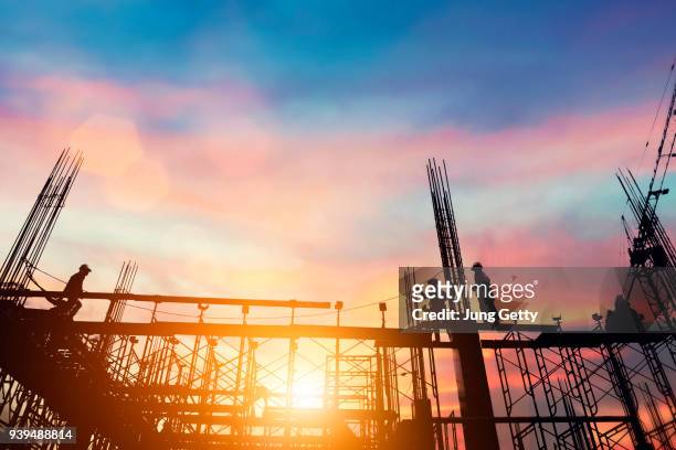 silhouette civil site engineer and construction worker working on scaffolding in industrial construction during sunset sky background over time job - civil engineering fotografías e imágenes de stock