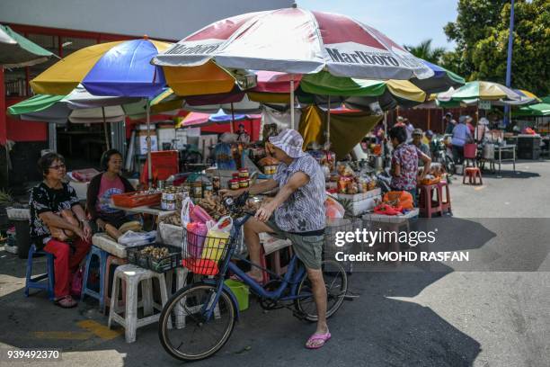 Woman shops for ginger at a roadside stall in Bentong, outside Kuala Lumpur in nearby Pahang state on March 29, 2018. / AFP PHOTO / Mohd RASFAN