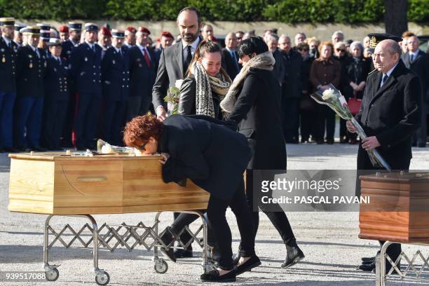 French Prime Minister Edouard Philippe and French Interior Minister Gerard Collomb stands by as family members pay their last respects during the...