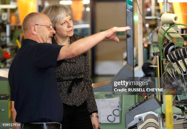 Britain's Prime Minister Theresa May talks with a member of staff as she visits textile producers Alex Begg in Ayr, Scotland, March 29 during a tour...