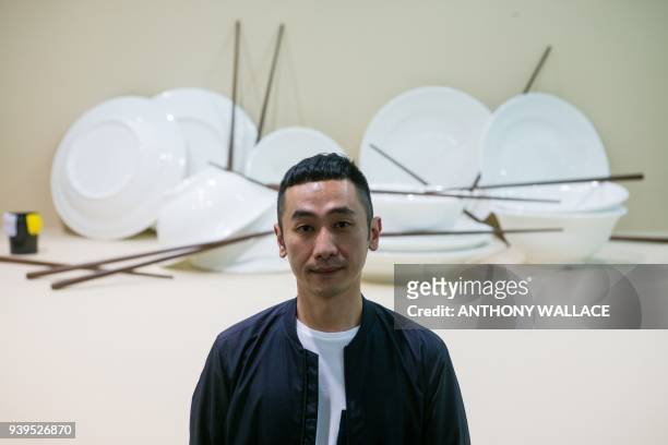 In this picture taken on March 27 Taiwanese artist Chou Yu-Cheng poses in front of his artwork "Refresh, Sacrifice, New Hygiene, Infection, Clean,...