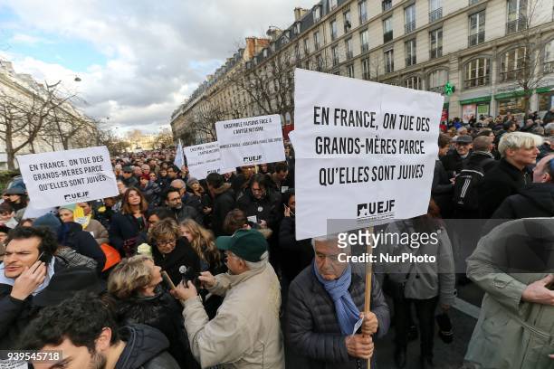Demonstrator hold a sign reading « In France, we kill grandmothers because they are Jewish » during a silent march in Paris on March 28 in memory of...
