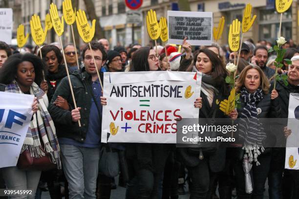 Demonstrators hold signs against anti-Semitism during a silent march in Paris on March 28 in memory of Mireille Knoll, an 85-year-old Jewish woman...