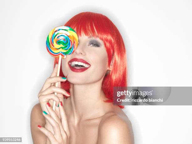 girl with red hair eating a lollipop - lolly models stockfoto's en -beelden