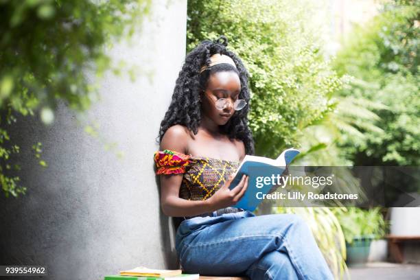 young woman looking at book in city garden - lilly roadstones stock pictures, royalty-free photos & images