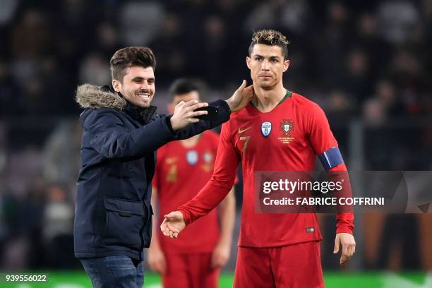 Fan takes a selfie with Portugal's forward Cristiano Ronaldo after invading the field during the international friendly football match between...