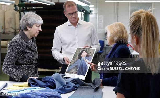 Britain's Prime Minister Theresa May looks at textiles as she visits textile producers Alex Begg in Ayr, Scotland, March 29 during a tour of the...