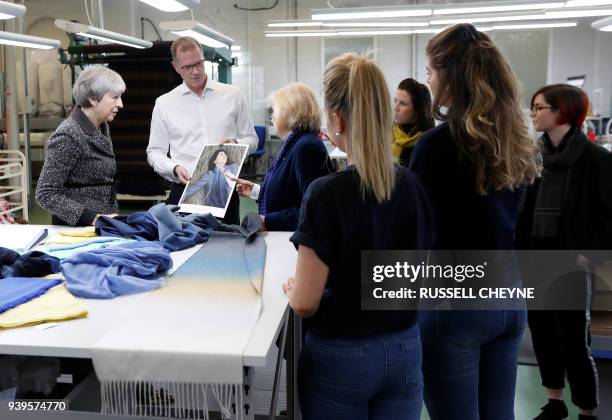 Britain's Prime Minister Theresa May looks at textiles as she visits textile producers Alex Begg in Ayr, Scotland, March 29 during a tour of the...