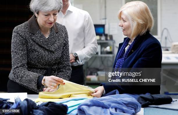 Britain's Prime Minister Theresa May looks at textiles as she visits textile producers Alex Begg in Ayr, Scotland, March 29 during a tour of the...