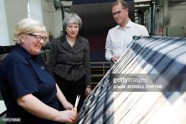 Britain's Prime Minister Theresa May looks at textiles as she visits textile producers Alex Begg in Ayr, Scotland, March 29 during a tour of the...