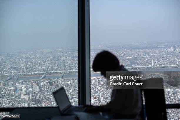 Cafe employee works on her laptop on the viewing platform of the Tokyo Skytree on March 29, 2018 in Tokyo, Japan. The tower was opened to the public...