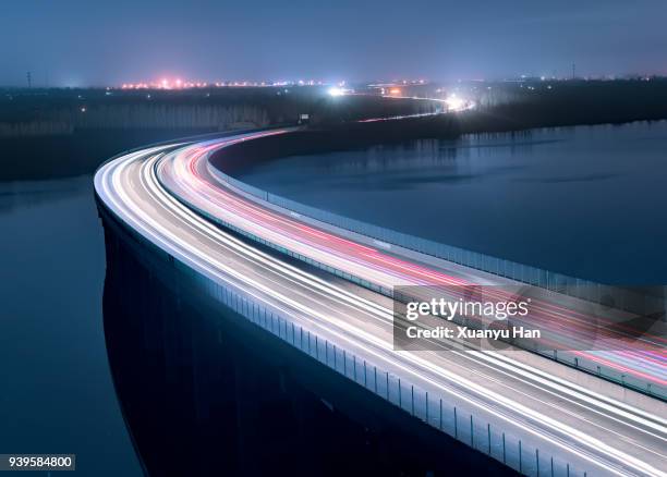 a bridge above a lake at night - digital highway stock pictures, royalty-free photos & images