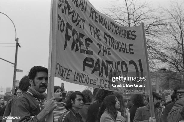 In a crowd, a pair of men hold a banner that reads, in part, 'Dominican Revolutionaries Support the Struggle to Free the Panther 21,' during a...