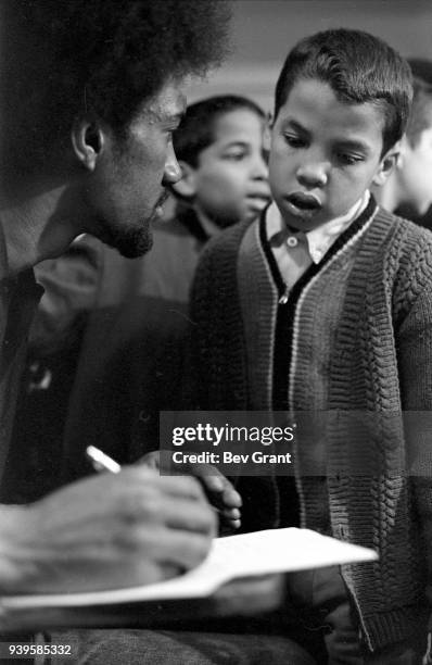 Close-up of an unidentified man as he writes in a notebook while talking to young boy during a free breakfast for children program sponsored by the...