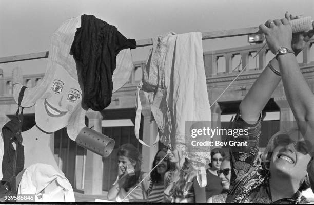 On the Atlantic City Boardwalk, a demonstrator holds up a Miss America marionette draped in underwear, high heels, and hair curlers during a protest...