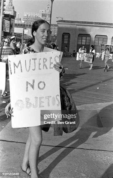 On the Atlantic City Boardwalk, a demonstrator carries a poster that reads 'Mujeres! No Objetos' as, with others, she protests the Miss America...