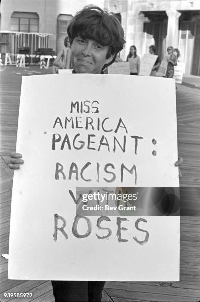 Portrait of a demonstrator as she holds a poster that reads 'Miss America Pageant: Racism with Roses' as she poses on the Atlantic City Boardwalk...